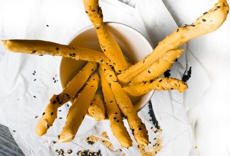 homemade snack, baked sticks with sesame and black cumin in the paper cup and in white napkin....