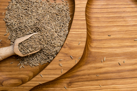 aromatic dried cumin in wooden spoon in wooden backgroundの写真素材