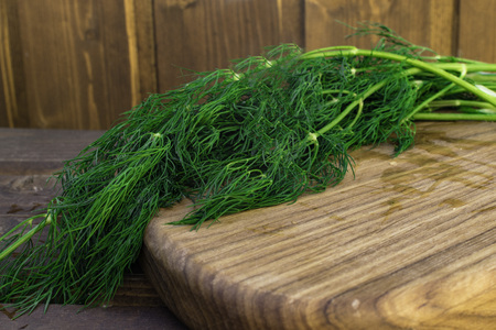 Bunch of dill isolated on a wooden background in wood board with space for text. Selective focus....