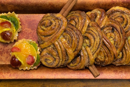 sweet cinamon buns and fruit cakes. Unhealthy food and diet time concept. Wooden background