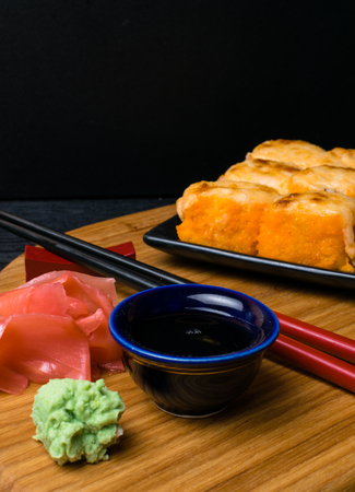 Hot fried Sushi Roll with salmon, caviar, shrimp, cucumber, avokado, cheese. Sushi menu. Japanese food with wasabi, ginger, soy souce. Hot fried Sushi Rollの写真素材