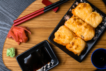 Hot fried Sushi Roll with salmon, caviar, shrimp, cucumber, avokado, cheese. Sushi menu. Japanese food with wasabi, ginger, soy souce. Hot fried Sushi Rollの写真素材
