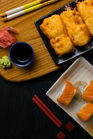 mix of sushi with cheese, salmon, shrimps, avokado, cucumber. Japan food with chopsticks, ginger, wasabi, soy souce on wooden board. Sushi menuの写真素材