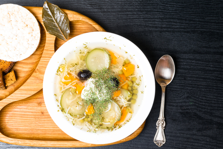 Raw squash and zucchini soup with carrot, pumpkin, pea, dill, black olives, bay leaf. Vegetable, vegetarian soup on wooden background. Children soup with bread,crumbs and galetteの写真素材