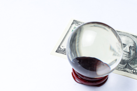 Hundred dollar bill under a magnifying glass ball is being inspected Conceptual photo isolated on white background. Selective focusの写真素材