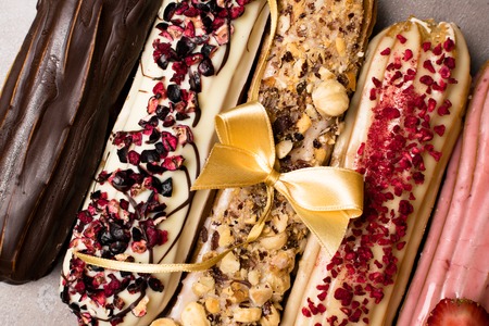 Sweet delicious colorful french eclairs. Group of french dessert with bow. Eclair background. French...