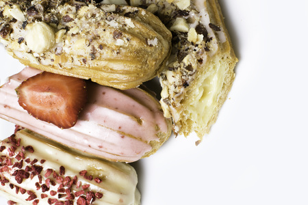 Sweet delicious colorful french eclairs. Group of french dessert. Eclair background. French pastry glazed eclairs, decorated with raspberries, cream and chocolate. Variety Selectionの写真素材