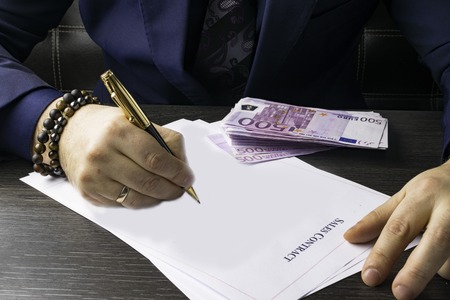 Business man writing a payment check contract at the table and working on documents in the...