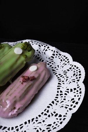 French traditional eclair, decorated with raspberry and cream on the dark wood tableの写真素材