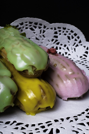 French traditional eclair, decorated with raspberry and cream on the dark wood table