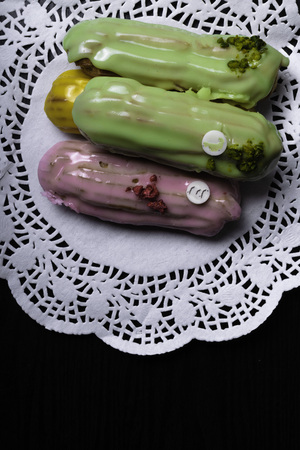 French traditional eclair, decorated with raspberry and cream on the dark wood table