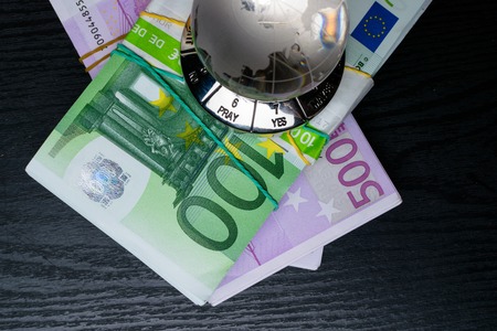 glass earth with choice yes or no, and big amount euro cash on the black wooden background