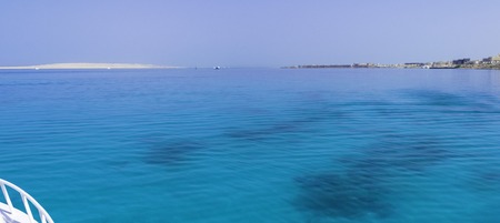 Landscape of transparent blue periling sea salt water, sea, ocean with waves with a bottom of beautiful coral reefs, stones against the backdrop of distant mountains.の写真素材