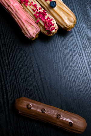 French traditional eclair, decorated with raspberry, blueberry,cream and coffee beans on black...
