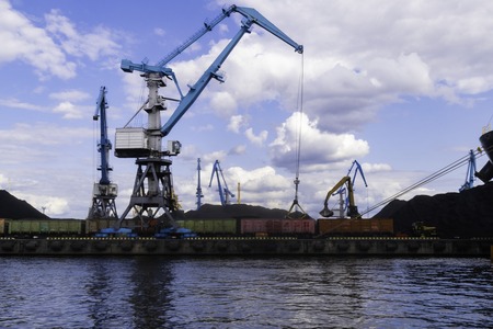 Large red cargo ship loading with a coal in the port, terminal, crane, container