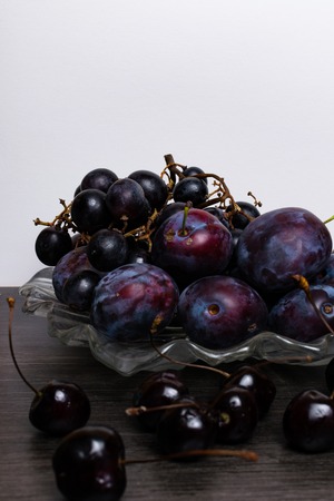 still life with plum, grape, cherry on grey table, white background. Healthy eating. Vegan foodの写真素材