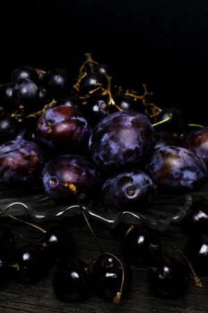 still life with plum, grape, cherry on wooden table, black background. Healthy eating. Vegan foodの写真素材