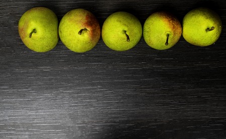 fresh green ripe pear on black wooden background. autumn harvest of fruits, rich with vitamins