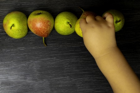 fresh green ripe pear on black wooden background. autumn harvest of fruits, rich with vitamins, baby...
