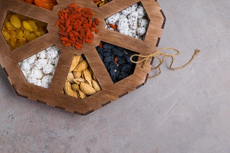 Mixed Nuts on grey background, as apricot, raisins, walnuts, goji, peanuts in glaze, almonds Healthy...