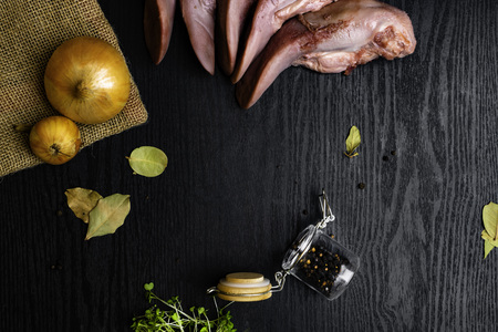 raw pork or beef tongues with black pepper in glass jar, bay leafs, onion on sackcloth, cress salad on black wooden table, gourment food conceptionの写真素材