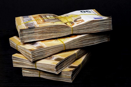 Pile of 50 real euro notes 50-euro banknotes under rubber band, isolated on black background. About 2500 euros worthの写真素材