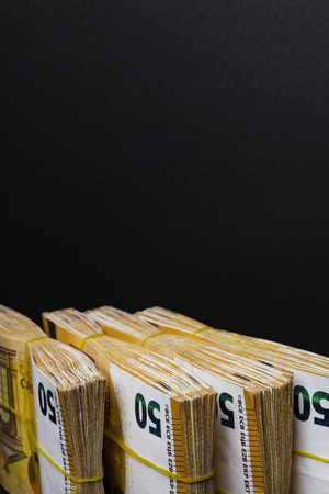 Pile of 50 real euro notes 50-euro banknotes under rubber band, isolated on black background. About 2500 euros worthの写真素材