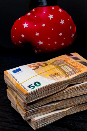 red with stars boxing glove and cash money. Concept of bribery, dishonesty in sport, greed. Isolated on blackの写真素材