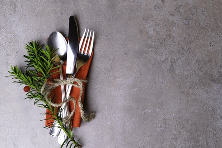 High Angle View of Silver Cutlery Set Wrapped in rope with Christmas tree branch , red berry on Stylish grey stone background, Christmas dinner plate decoration. Merry christmas card. Winter holiday theme. Happy New Year. Space for text.の写真素材