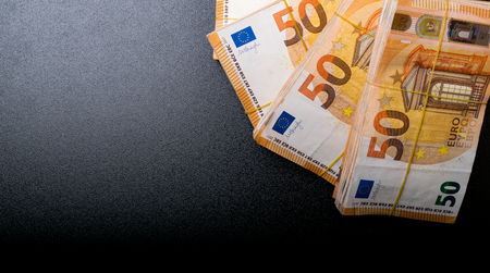 Pile of 50 real euro notes 50-euro banknotes under rubber band isolated on black backgrund About 20000 euros worth.の写真素材