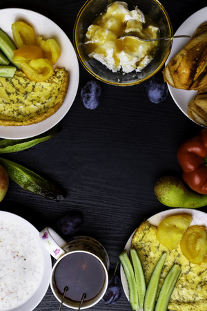 Ingredients of healthy dietary food breakfast green leafs, tomatoes, pear, cottage cheese, omelette with dill, apple, pepper, porridge, toasts, honey with cup of black tea on wooden background. Vegetarian friendly. Top View copy spaceの写真素材
