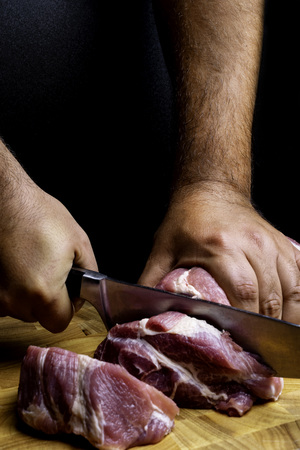 Male Chef Preparing Meat Stakes. Close Up Male In The Kitchen Is Cutting Pork On Cutting Board. Cutting The Meat Into Slices With A Knife. Image For Templates, Placards, Banners, Presentations, Reportの写真素材