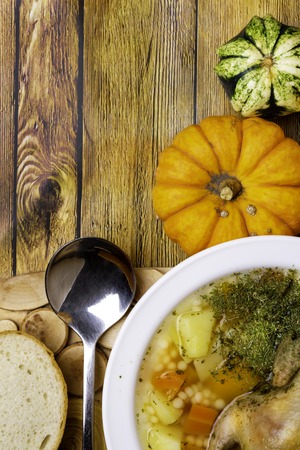 Quail pumpkin Soup, Homemade Broth with couscous and Vegetables Served with Bread on wooden table, small pumpkinの写真素材