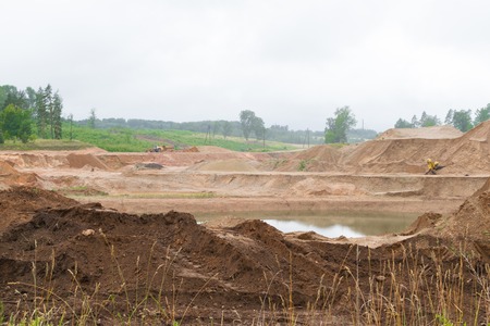 yellow excavator and tractor at sandpit with water during earthmoving worksの写真素材
