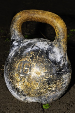 An old cast-iron sports weight on the ground. Inventory for power sport of bodybuilding.の写真素材
