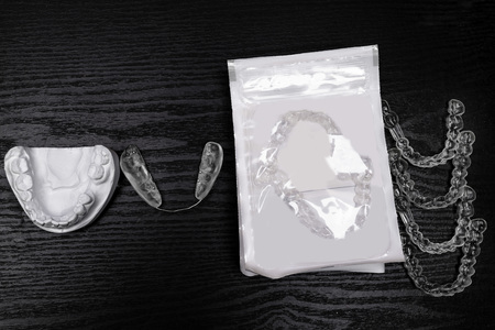 teeth alignment process, gypsum cast, different aligners in packing, straighten your teeth concept on black backgroundの写真素材