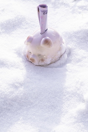 ceramic piggy bank with 500 euro cash on snow backgroundの写真素材