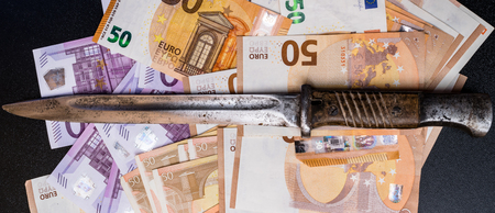 The concept of money is to share, euro money notes with a bayonete knife. Business, crime conceptの写真素材