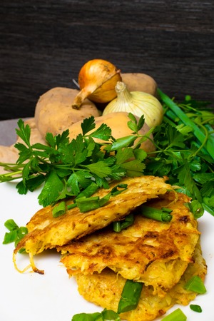 Fried savory tuna pancakes with potato, onion and parsley on white plateの写真素材