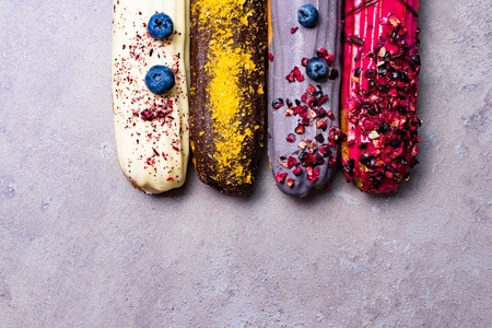 Sweet and colorful eclairs with berry Group of french dessert Eclair on violet background. custard...