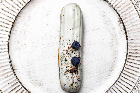 Tasty white chocolate eclair cake with cream and blueberry, copy space