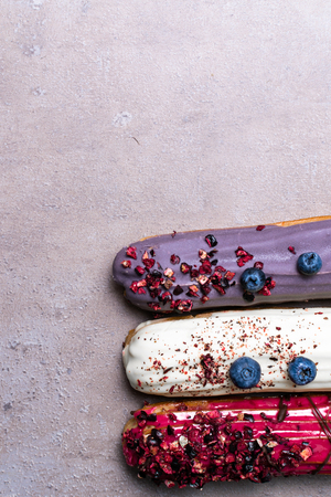 Group of french delicious colorful dessert Eclair on stone background copy space