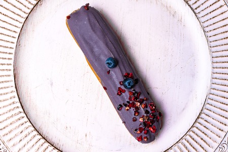 Delicious eclair on white background, top view