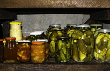 Preserves in jars salads, jam, cucumbers in home basement. Close up of stocks kept for the winterの写真素材