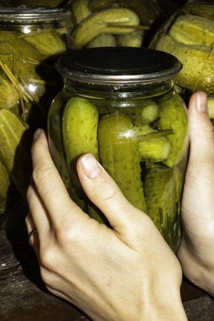 Woman puts pickled jars with cucumbers in the basement, for storage for a long time.の写真素材