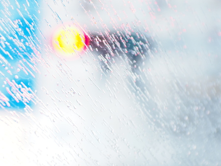Raindrops on the windshield on a rainy day, traffic light background, blurred, no focus