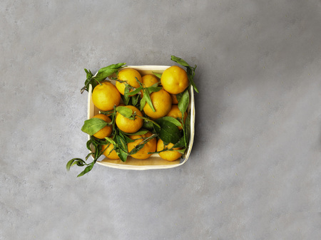Orange fruits in wooden box on dark stone table. Heap of oranges in box. Fresh juicy orange with leavesの写真素材