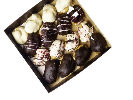 mini chocolate eclairs, isolated on white with raspberry, black and white chocolate