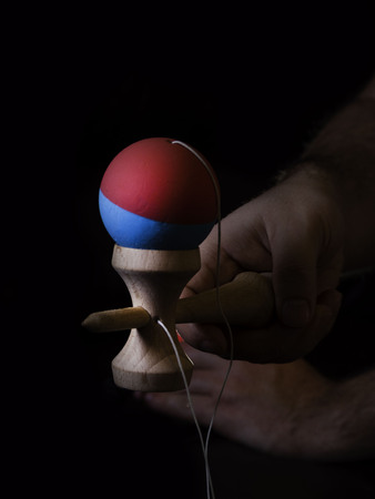 Classic Japanese game kendama on black background. Two boys hands playing kendamaの写真素材