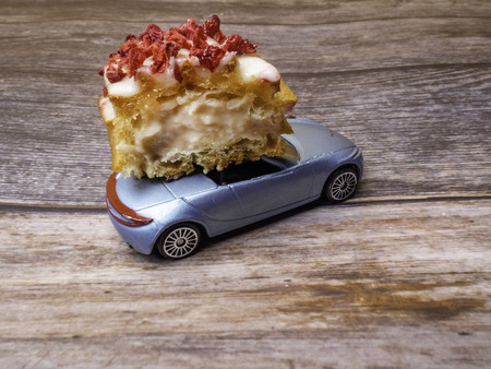 cut piece of berry eclair on toy car on wooden futage, order and delivery concept with copy spaceの写真素材